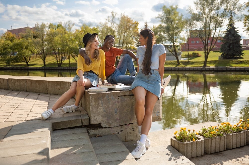 Grupo de jóvenes disfrutando al aire libre en uno de los lugares para visitar en España, compartiendo risas junto a un canal rodeado de naturaleza