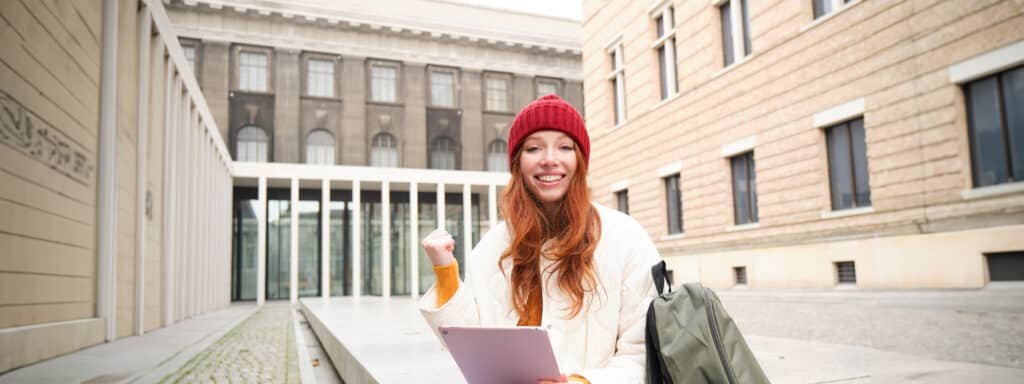 Estudiante feliz frente a la universidad tras elegir una de las mejores carreras para estudiar en España.