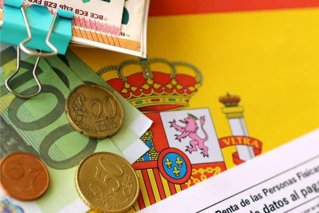 Monedas y billetes de euro sobre una bandera de España, representando el coste de vida en España