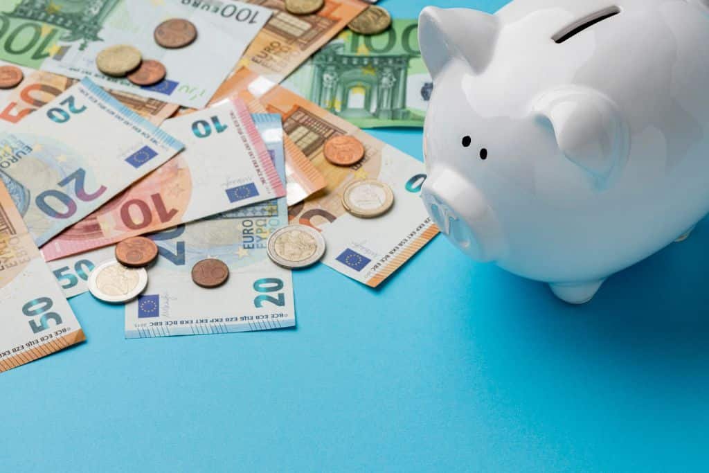 Hucha y billetes sobre fondo azul representando el coste de vida en España
