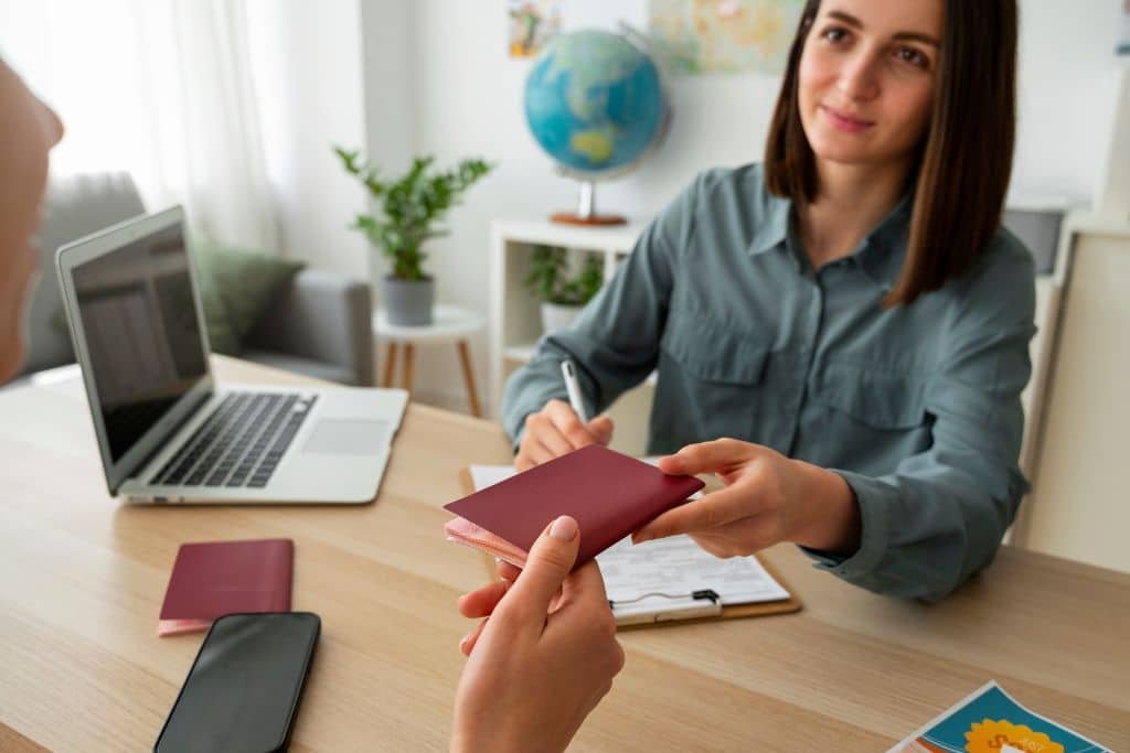 Asesora entregando pasaporte a solicitante en oficina: requisitos para renovar el NIE en España.