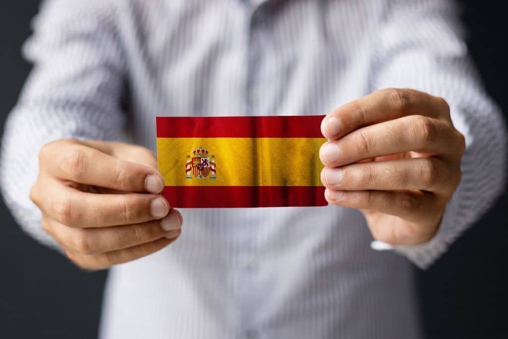 Persona sujetando una bandera de España representando los tipos de arraigo en España