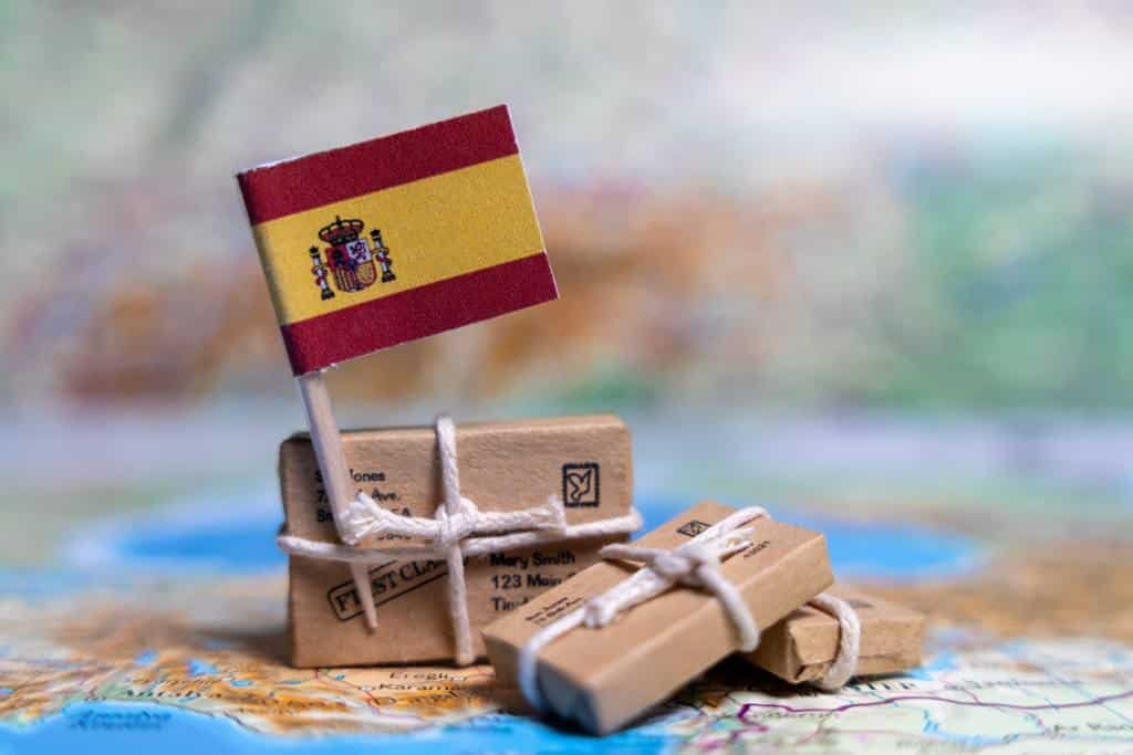 Tipos de permisos de residencia en España: bandera y maletas sobre un mapa representando una mudanza